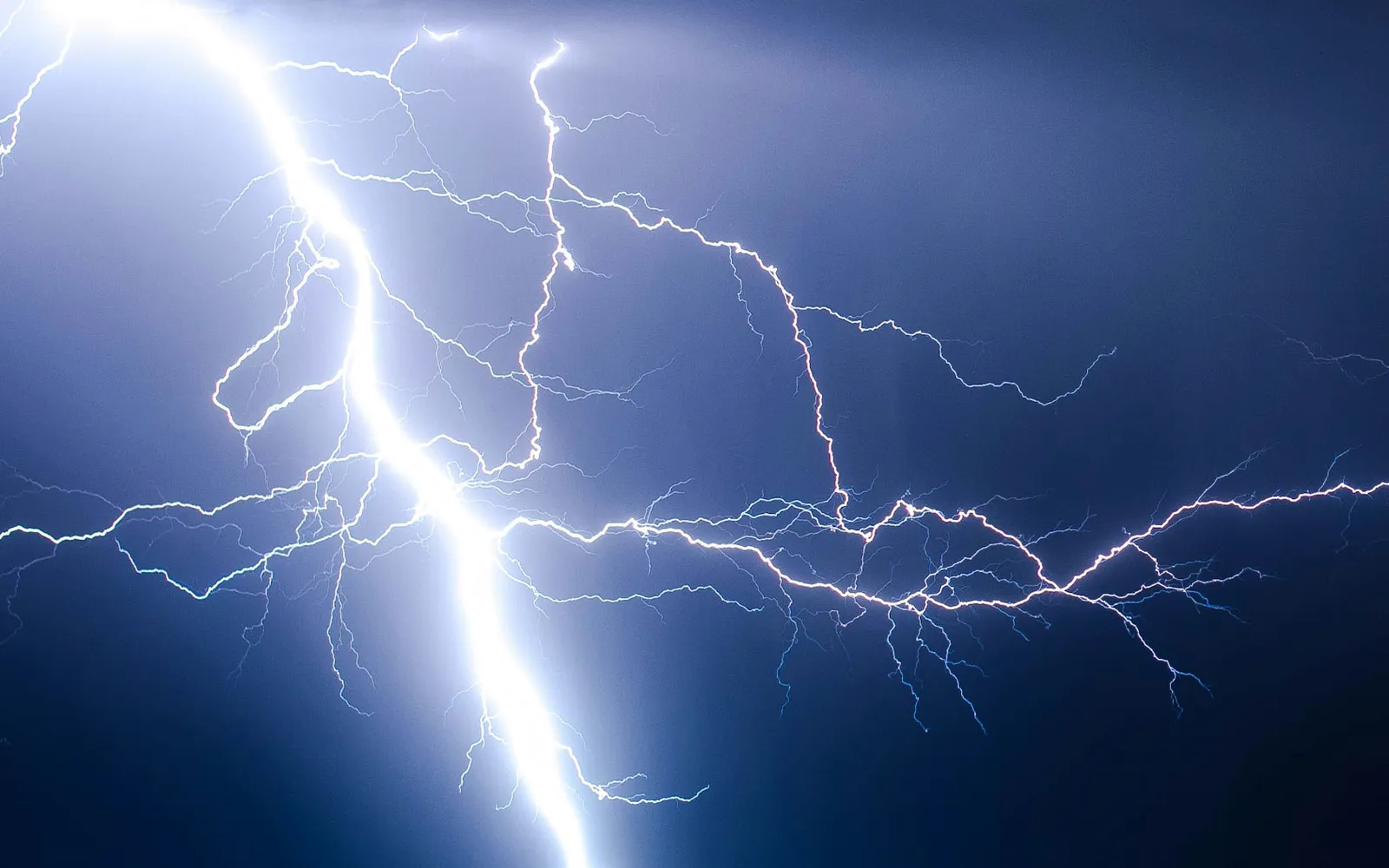 Blitzeinschlag bei Nacht unter dunkler Gewitterwolke.